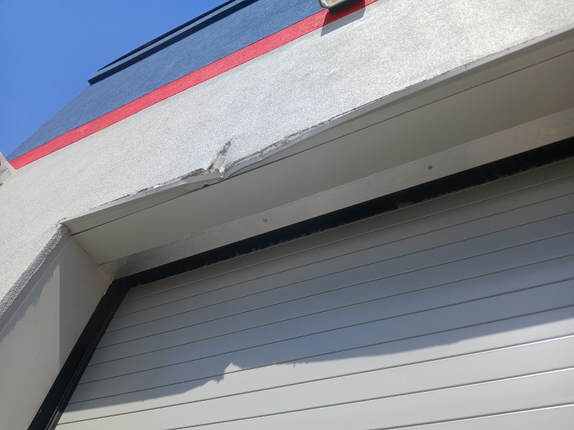Damaged exterior finish and trim above a commercial roll-up door