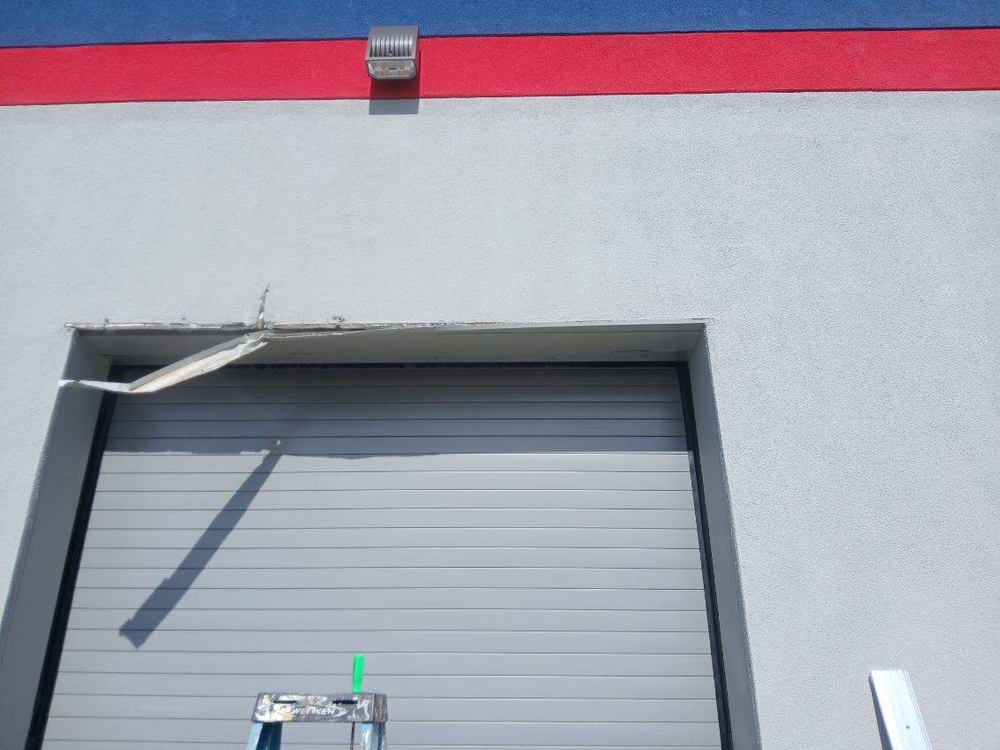 Commercial roll-up-door opening with damaged exterior header finish