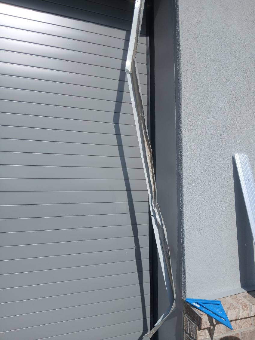Bent and detached metal trim beside a commercial roll-up door