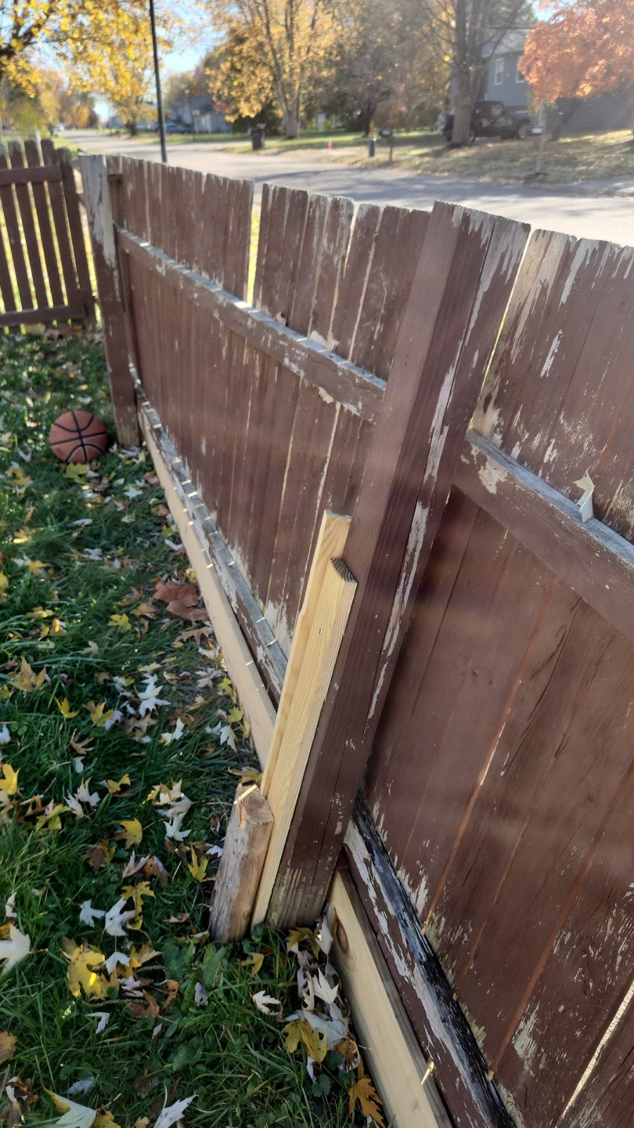 Damaged wood fence supported by temporary bracing