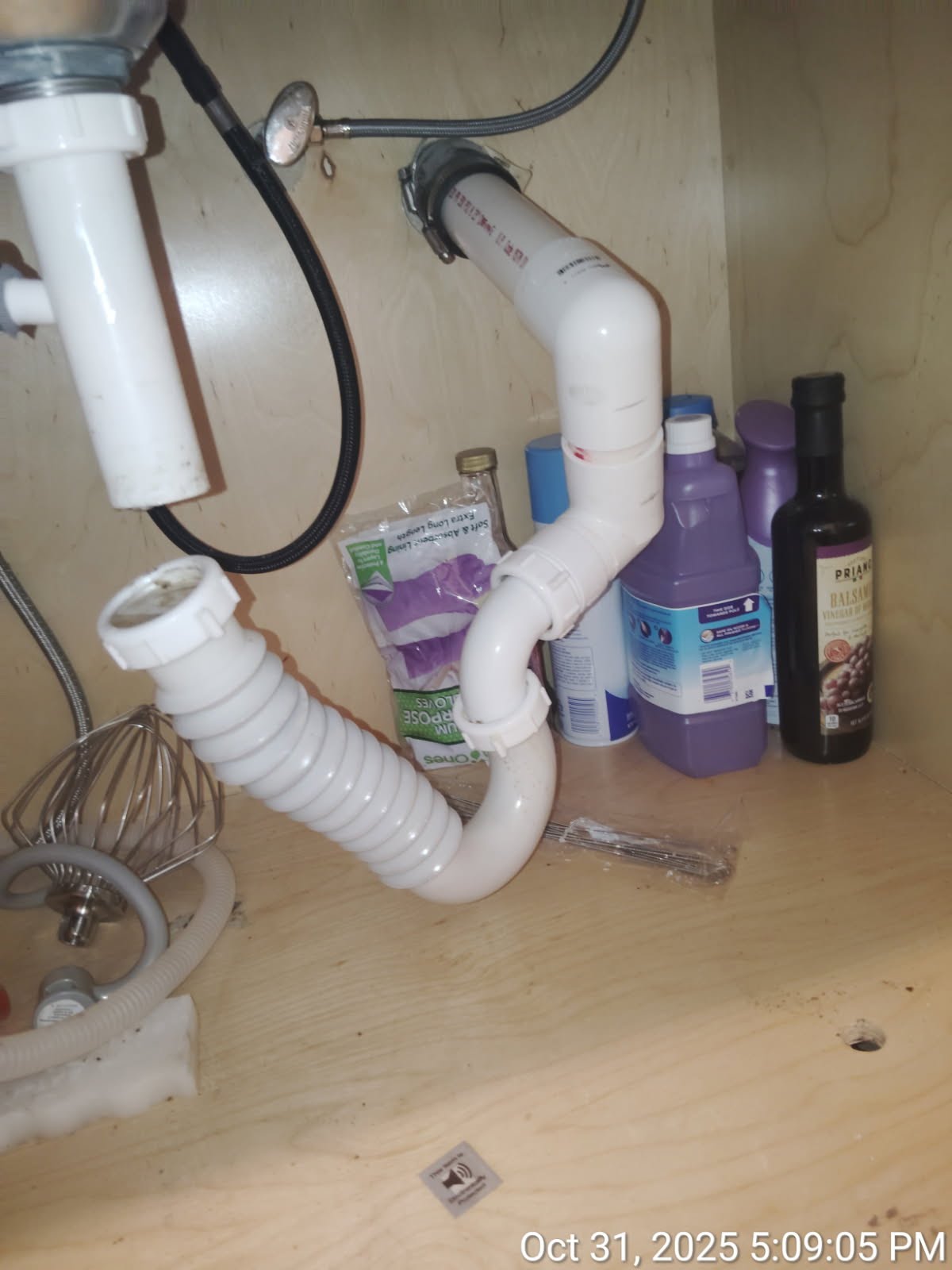 Sink drain, trap, and supply connections beneath a cabinet